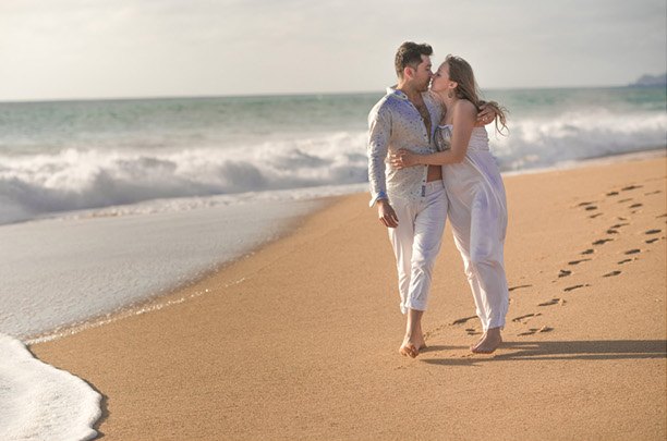 Pareja caminando descalza por la orilla de la playa